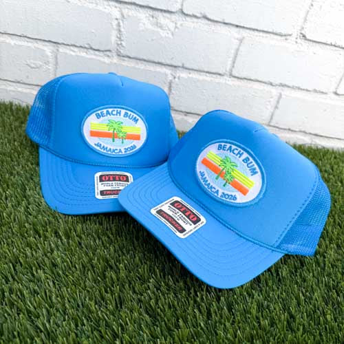 Turquoise blue trucker hats with oval palm tree patch, sunset stripes and Beach Bum Jamaica text